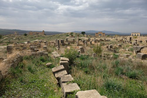 Free Explore the ancient ruins set against a cloudy Moroccan landscape, perfect for history and travel enthusiasts. Stock Photo