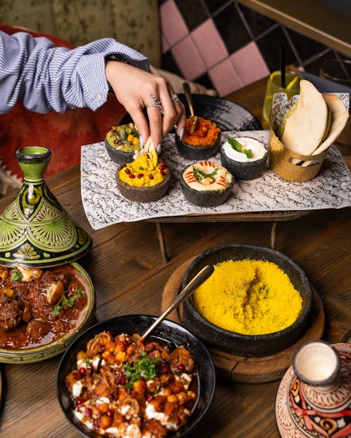 Free A vibrant Moroccan meal featuring beef tagine, various dips, bread, and yellow couscous, perfect for a cultural culinary experience. Stock Photo