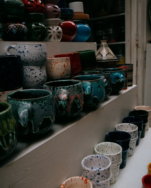 Free Vibrant array of Moroccan ceramic mugs and vases on market shelves in Essaouira. Stock Photo