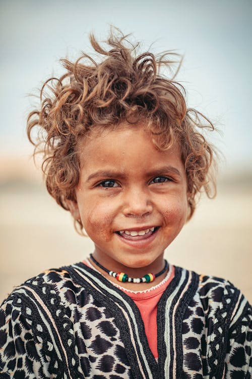 Free A joyful child with curly hair in traditional clothing, Merzouga, Morocco. Stock Photo