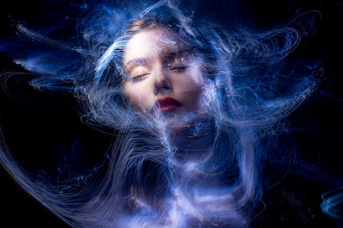 Free Abstract portrait of a woman with swirling blue light trails and closed eyes. learn deep connection