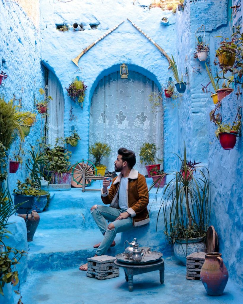 man sitting on blue painted room with plants