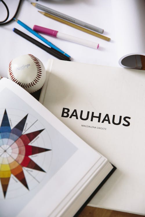 Free An artistic workspace featuring a Bauhaus design book, art supplies, and a baseball for inspiration. Stock Photo