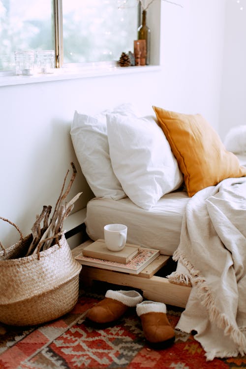 Free A cozy bedroom setup featuring pillows, a blanket, and warm-toned decor. Stock Photo