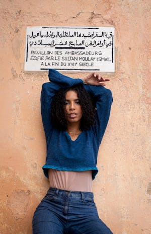 Moroccan model posing next to a sign written in arabic and french