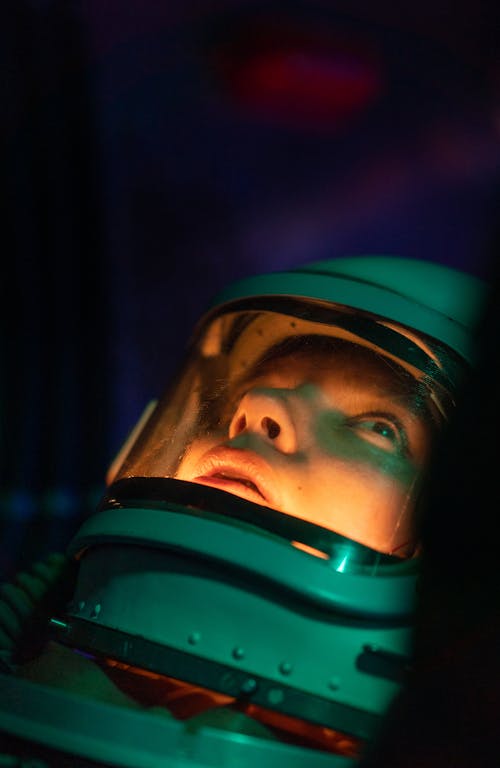 Free A female moroccan astronaut in a space suit looks up, illuminated by cosmic light. Stock Photo