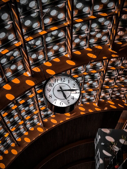 Free A striking black and white clock hangs in a sunlit train station interior with a spotted ceiling pattern in Rabat. Stock Photo