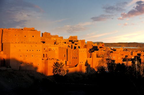 Free Majestic sunset over the traditional Kasbah in Ouarzazate, Morocco, highlighting the warm reddish tones. Stock Photo