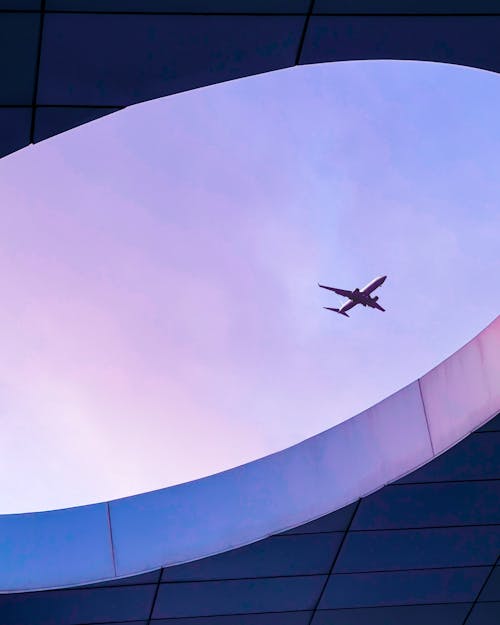 Free A sleek airplane flies over modern architectural structure in Casablanca, Morocco. Stock Photo