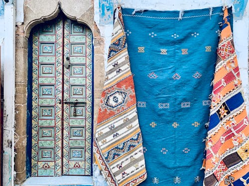Free Ornate doorway with vibrant woven rugs, showcasing cultural artistry and vibrant patterns. Stock Photo
