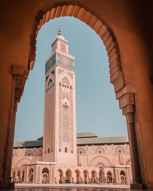 Free Elegant view of the Hassan II Mosque minaret through an ornate archway in Casablanca Morocco. Stock Photo