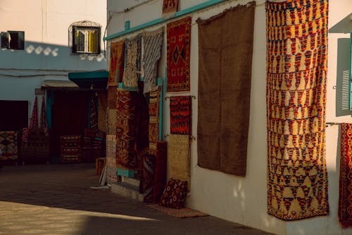Free Colorful handwoven Moroccan rugs on display in a vibrant Asilah market. Stock Photo