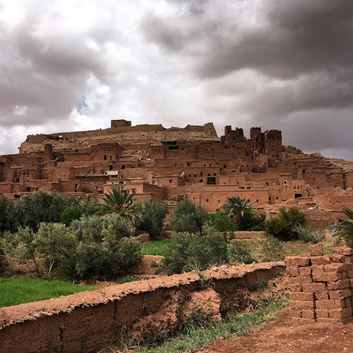 Free Explore the ancient clay architecture of Aït Ben Haddou under dramatic skies, a UNESCO World Heritage Site. Stock Photo