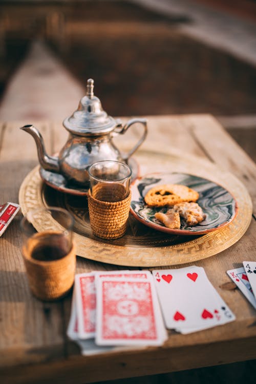 Free Authentic Moroccan tea setup with playing cards on a rustic wooden table in Marrakesh. Stock Photo