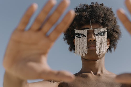 Free A creative outdoor portrait featuring a person with afro hair and unique beaded face ornament. Stock Photo