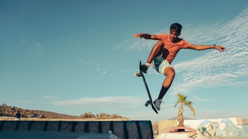 Free A skateboarder performs a high jump trick in a sunny Moroccan skatepark, showcasing athletic skill. Stock Photo