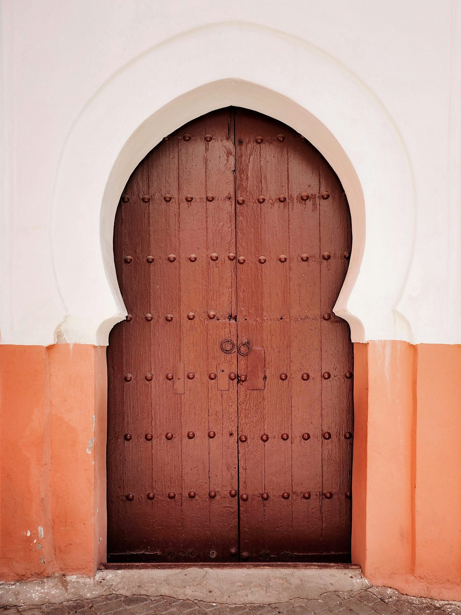 A large wooden door in front of a white building