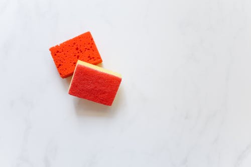 Free Two bright orange sponges suitable for cleaning against a white background. Stock Photo